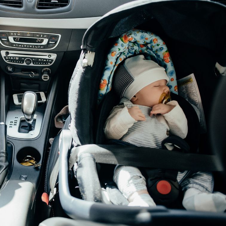Новорожденный в автолюльке на переднем кресле